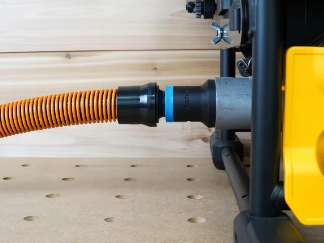 Black ToolCurve 1-1/4 inch hose adapter with blue band linking an orange vac hose to a DeWalt table saw dust port