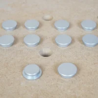 Ten 20mm aluminum bench dog hole button protectors with stepped underside, set on an MFT-style holed top