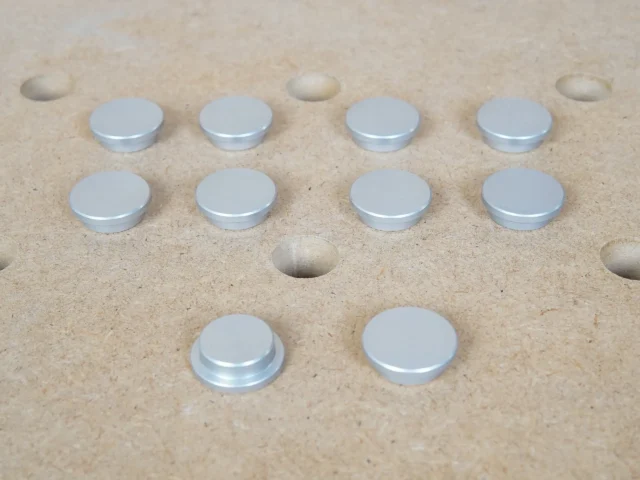 Ten 20mm aluminum bench dog hole button protectors with stepped underside, set on an MFT-style holed top
