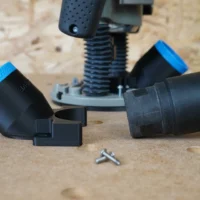 Black 36mm hose adapter with blue collar lying beside a Bosch 1617 plunge router base, dust hose cuff and two screws