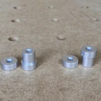 Four aluminum bench dogs with M8 threaded tops, shown on a perforated workbench with 20mm holes visible above