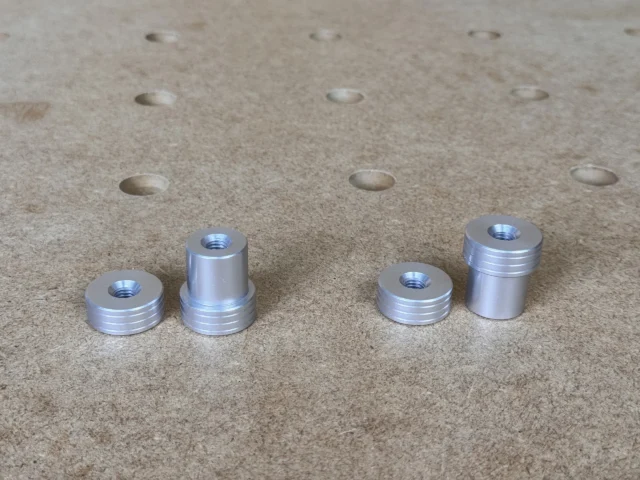 Four aluminum bench dogs with M8 threaded tops, shown on a perforated workbench with 20mm holes visible above