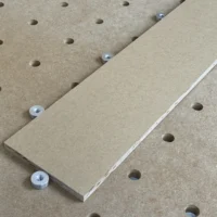Four 20mm aluminum bench dogs with M8 threaded bases positioned on a pegboard workbench surface