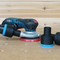 Black and blue ToolCurve 1-7/8 inch hose adapter fitted to a Bosch GEX sander, with two spare adapters beside it
