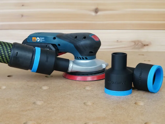 Black 36mm hose adapter with blue collar connecting a vacuum hose to a Bosch GEX sander, two spare adapters beside it