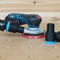 Black ToolCurve 1-1/4 inch hose adapter with blue ring installed on a Bosch GEX 18v sander, plus two spares