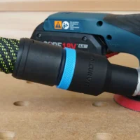 Black hose adapter with blue grip band attached to Bosch GEX 18v sander, connected to yellow and black dust hose