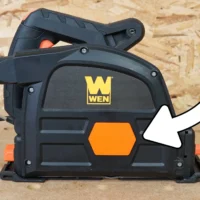 Side view of a WEN track saw on a workbench with a white arrow pointing to the arbor cover location