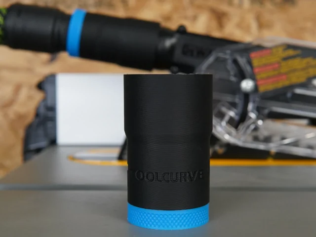 Black ToolCurve hose adapter with blue band, standing alone on workbench with Dewalt table saw in background