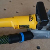 Black hose adapter attached to yellow DeWalt biscuit joiner dust port, with green and black hose connected below