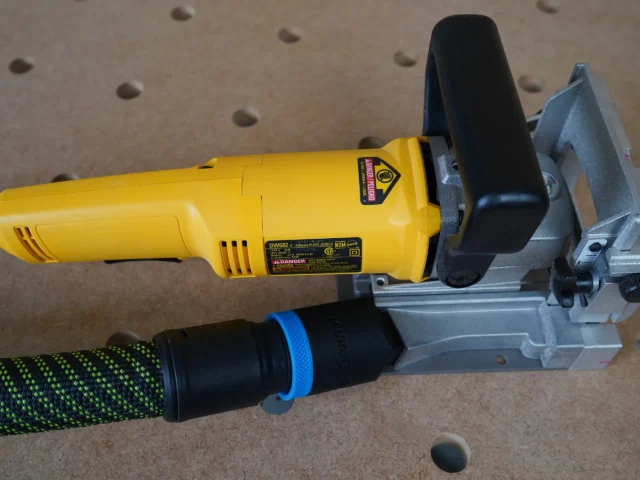 Black hose adapter attached to yellow DeWalt biscuit joiner dust port, with green and black hose connected below