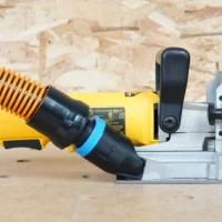 Hose adapter attached to DeWalt biscuit joiner dust port, connecting orange flex hose to white plastic mount