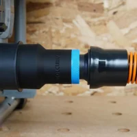 Black ToolCurve 1-1/4 inch hose adapter with blue band joining a SKIL table saw dust port to an orange hose