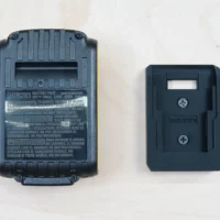 Black plastic battery holder mount next to a DeWalt 20v battery, showing the rectangular slot sized to accept the battery pack