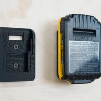 Black plastic battery mount for Dewalt 20v next to a DCB203 battery, showing the rectangular receptacle slot that accepts the battery