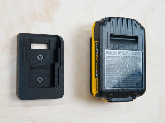 Black plastic battery mount for Dewalt 20v next to a DCB203 battery, showing the rectangular receptacle slot that accepts the battery