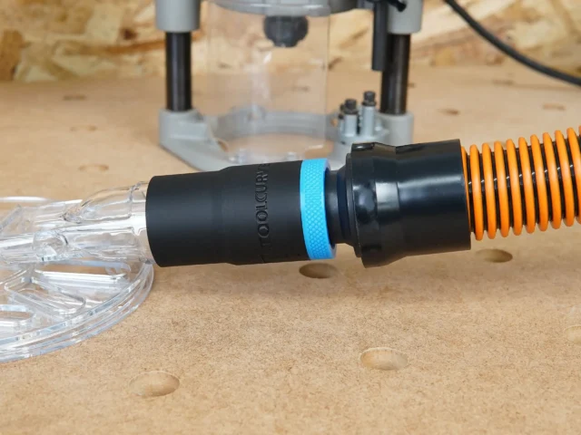 Black ToolCurve 1-1/4" hose adapter with blue ring joining an orange vac hose to a clear Oneida router hood