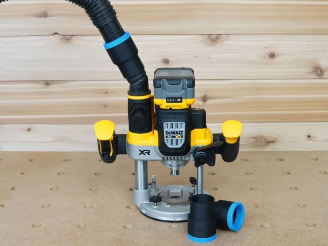 Black 1-7/8 inch hose adapter with blue cuff on a Dewalt cordless plunge router, second adapter on bench