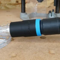 Black hose adapter with blue band connected to clear Oneida router hood dust port, with braided hose attached