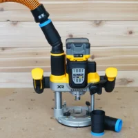 Black 1-1/4 inch hose adapter with blue band linking an orange vac hose to a DeWalt cordless plunge router, second adapter beside it