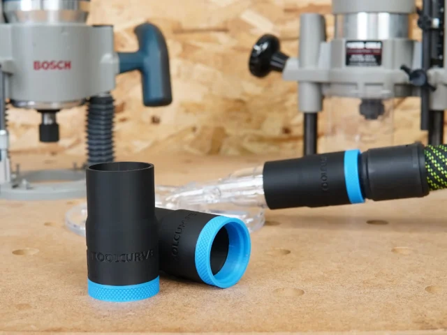 Black hose adapter with blue grip band for Oneida router hood, shown disconnected and connected to clear tubing on workbench
