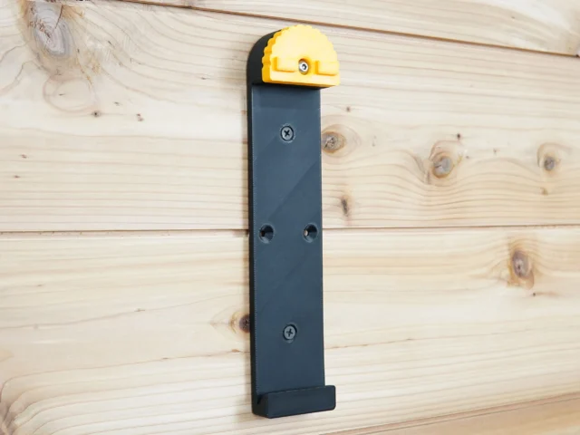Wall mount for Dewalt track saw rail with yellow locking lever, dark blue bracket, and three mounting holes on light wood