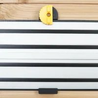 Yellow and black wall mount clipped onto Dewalt track saw rail mounted horizontally on wood wall