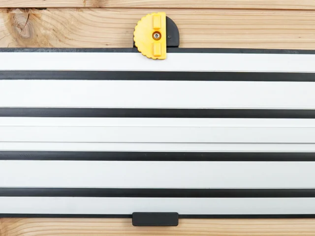 Yellow and black wall mount clipped onto Dewalt track saw rail mounted horizontally on wood wall