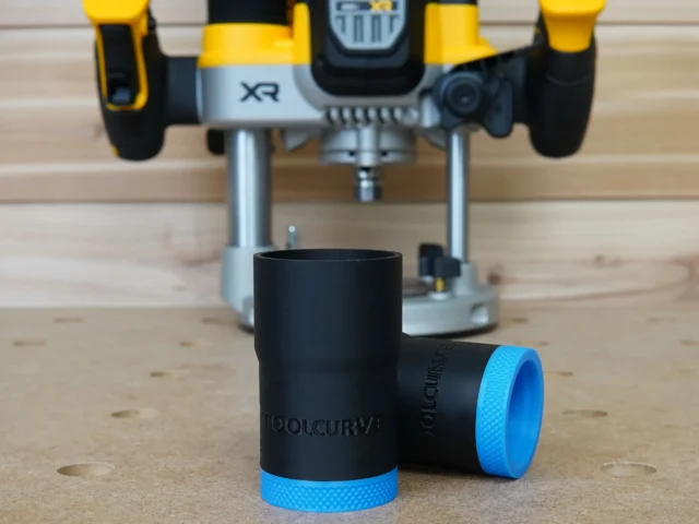 Black and blue hose adapter with ToolCurve branding, shown in front with DeWalt plunge router blurred in background