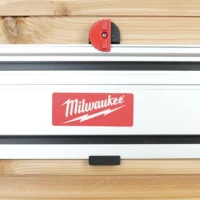 Red and black wall mount clipped onto a Milwaukee track saw rail mounted horizontally on wood