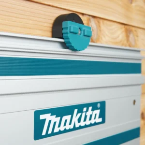 Teal and black wall mount holding a Makita guide rail against a wood-slat workshop wall, close-up view