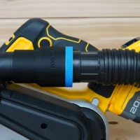 Black ToolCurve 1-7/8 inch hose adapter with blue band joining a ribbed vacuum hose to a DeWalt 20V belt sander dust port