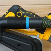 Black hose adapter with blue band attached to Dewalt belt sander dust port, connected to green-and-black braided hose