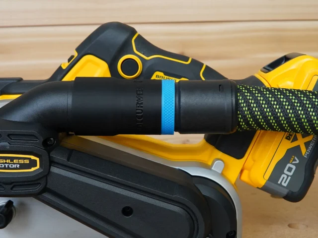 Black hose adapter with blue band attached to Dewalt belt sander dust port, connected to green-and-black braided hose