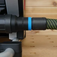 Black hose adapter with blue band attached to SawStop Compact table saw dust port, connected to green braided hose