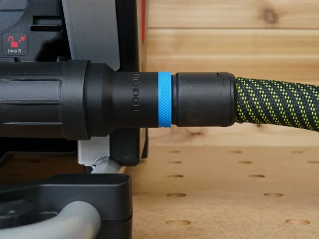 Black hose adapter with blue band attached to SawStop Compact table saw dust port, connected to green braided hose