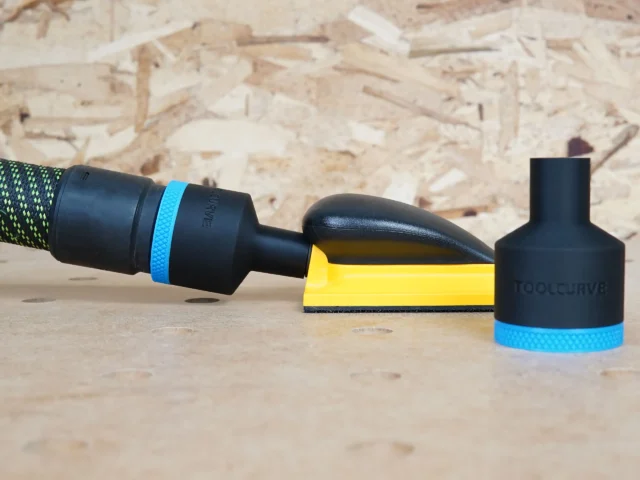 Black 36mm ToolCurve hose adapter with blue band joining a vacuum hose to a yellow Mirka hand sanding block, second adapter standing beside it