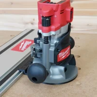 Milwaukee M18 2-1/4HP router with red housing mounted on gray guide rail adapter connected to aluminum track saw rail