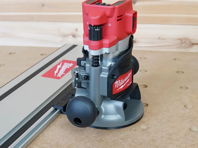 Milwaukee M18 2-1/4HP router with red housing mounted on gray guide rail adapter connected to aluminum track saw rail