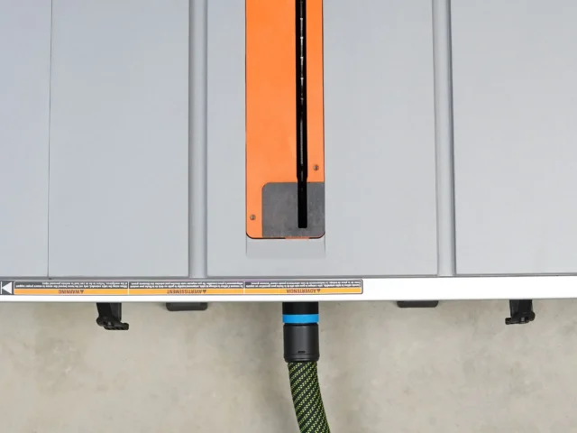 Orange and black hose adapter attached to Ridgid portable table saw's rear dust port, with green-wrapped hose connected below