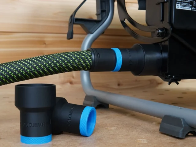 Black plastic hose adapter with blue band attached to green braided Festool hose, with a detached adapter shown on wood surface next to the tool