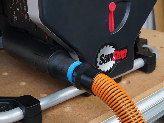 Black hose adapter attached to SawStop Compact table saw rear port, with blue and orange hose connectors visible
