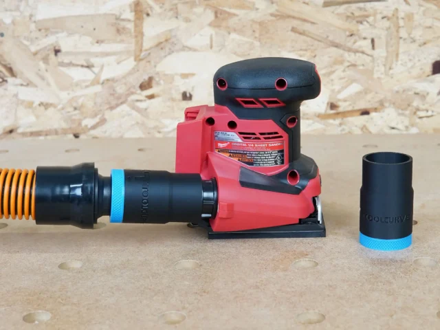 Black 1-1/4 inch ToolCurve hose adapter with blue band joining an orange hose to a Milwaukee sheet sander, spare adapter beside