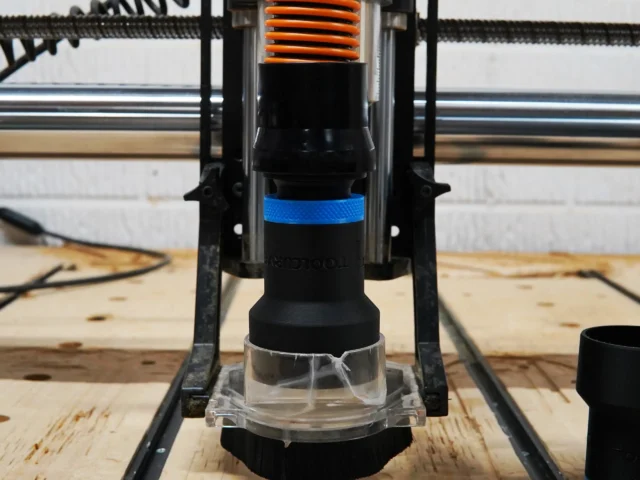 Black 1-1/4 inch hose adapter with blue collar installed on Onefinity CNC Suck It dust boot with brush skirt