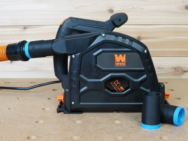 Black 1-1/4 inch hose adapter with blue collar joining an orange hose to a Wen track saw dust port, spare adapters beside it