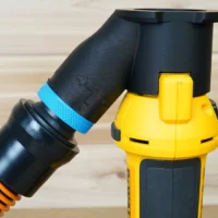 Black 1-1/4 inch hose adapter with blue band mounted on a yellow Dewalt drywall cut out tool, hose attached