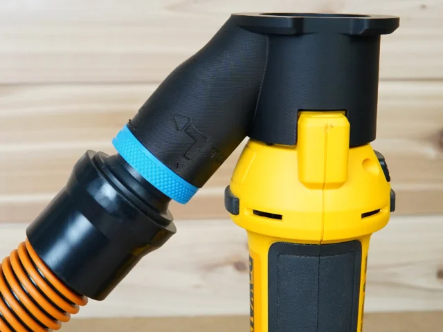 Black 1-1/4 inch hose adapter with blue band mounted on a yellow Dewalt drywall cut out tool, hose attached
