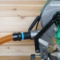 Black ToolCurve 1-1/4" hose adapter with blue band joining an orange hose to a Metabo HPT miter saw dust port