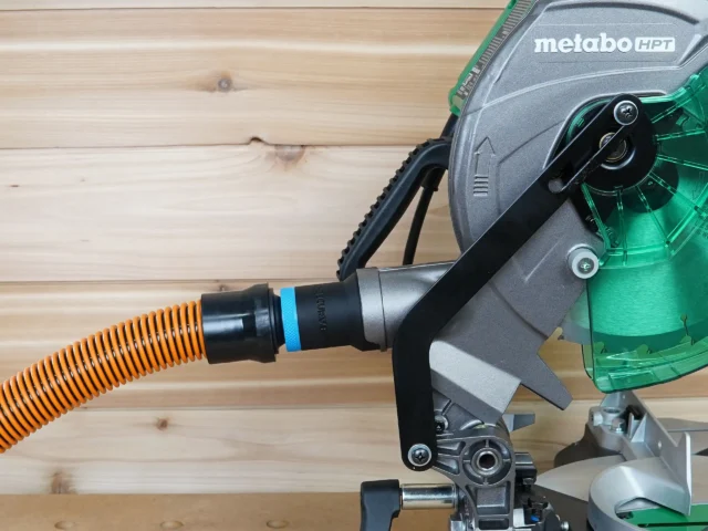 Black ToolCurve 1-1/4" hose adapter with blue band joining an orange hose to a Metabo HPT miter saw dust port