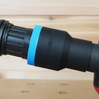 Black ToolCurve 1-7/8 inch hose adapter with blue grip ring joining a vacuum hose to a Milwaukee track saw port